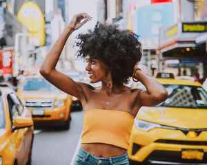一名头发自然的黑人妇女站在时代广场的出租车前