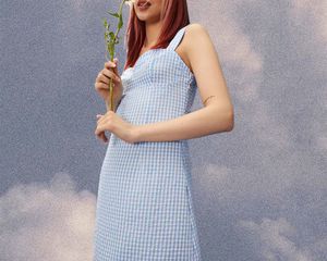 模特穿着泡泡纱蓝色裙子拿着一朵花。