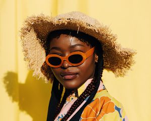 女人与盒子的辫子穿橙色太阳镜和编织的太阳的帽子