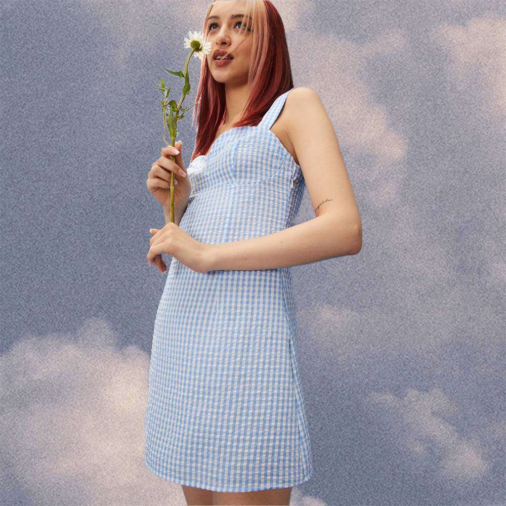 模特身穿泡泡纱蓝色连衣裙，手捧一朵花。