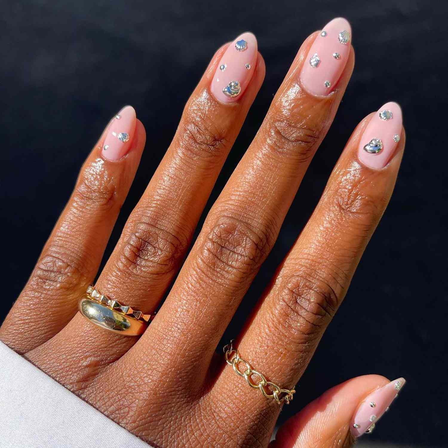 淡粉色的指甲上镶嵌着闪闪发光的宝石