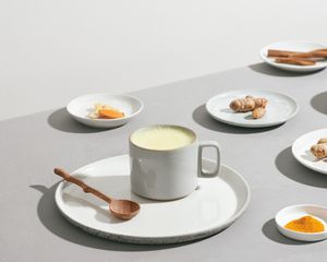 灰色的桌子上放着牛奶，姜黄，姜和肉桂。