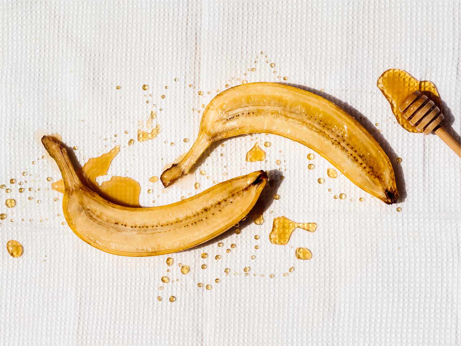 一个香蕉一分为二在白色背景下毛毛雨用蜂蜜