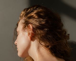 关闭一个女人的波浪赤褐色头发从后面,她的脖子