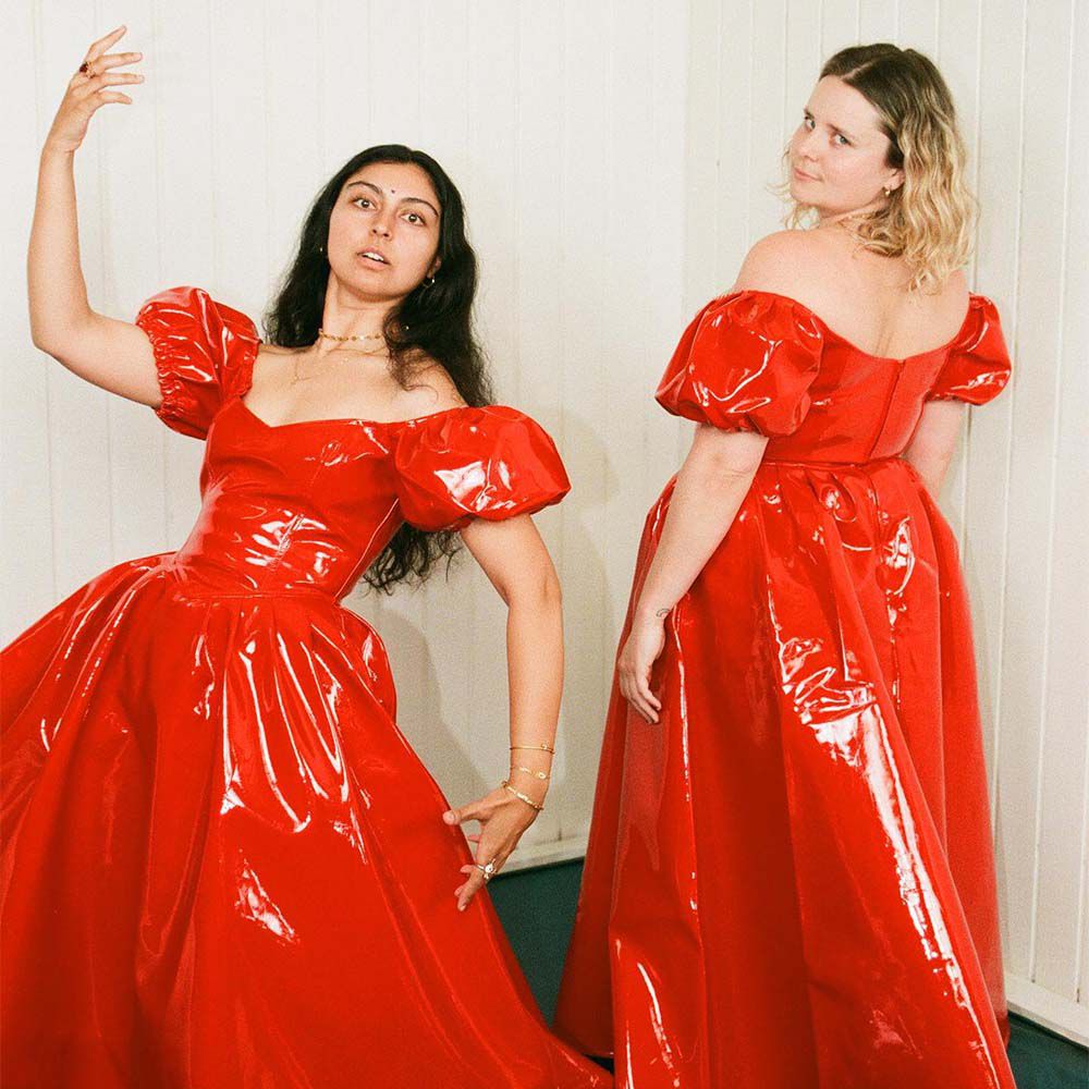 两个模特穿着一件红色乳胶蓬松袖长袍。