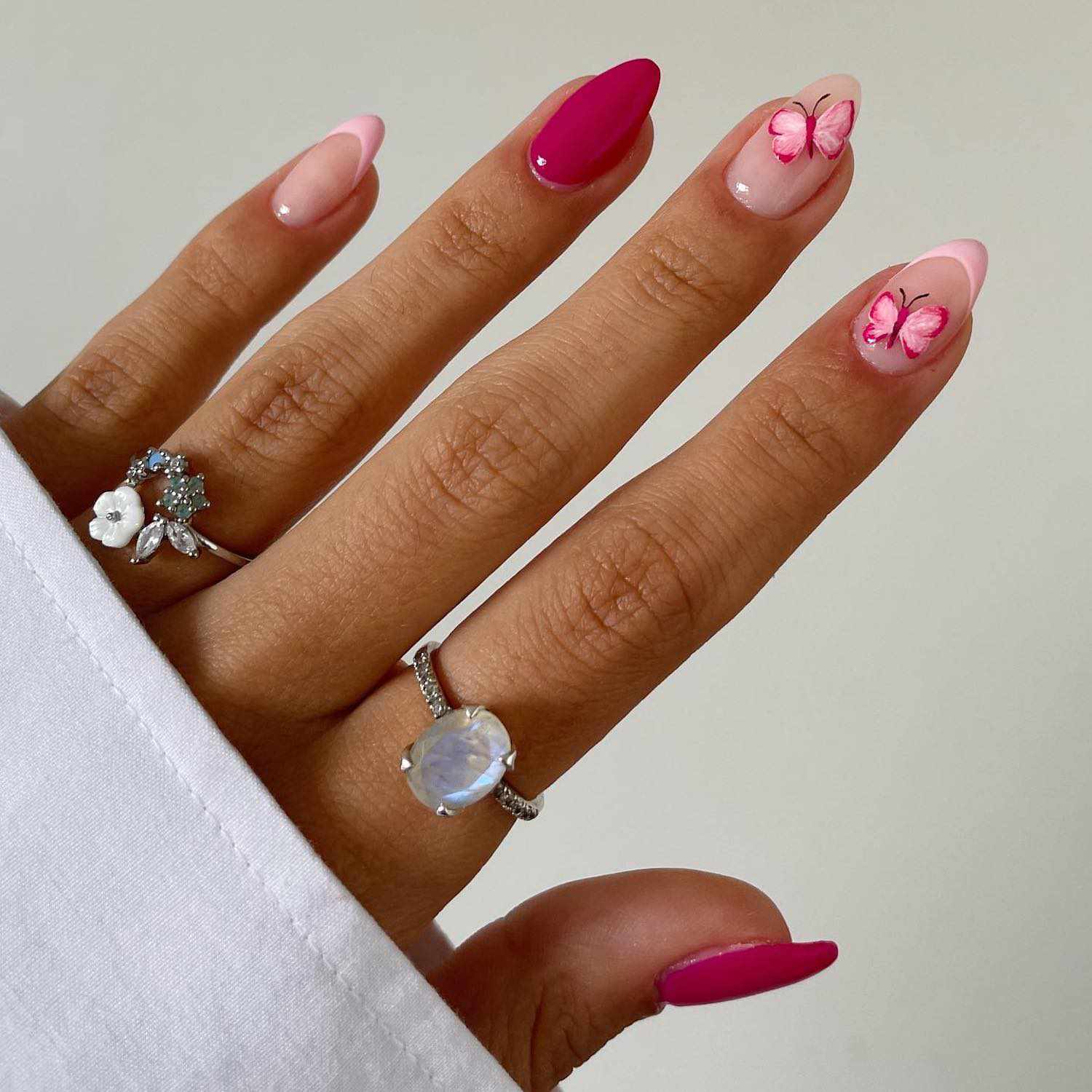 修指甲与固体粉红色指甲和淡粉色法国指甲与粉红蝴蝶设计