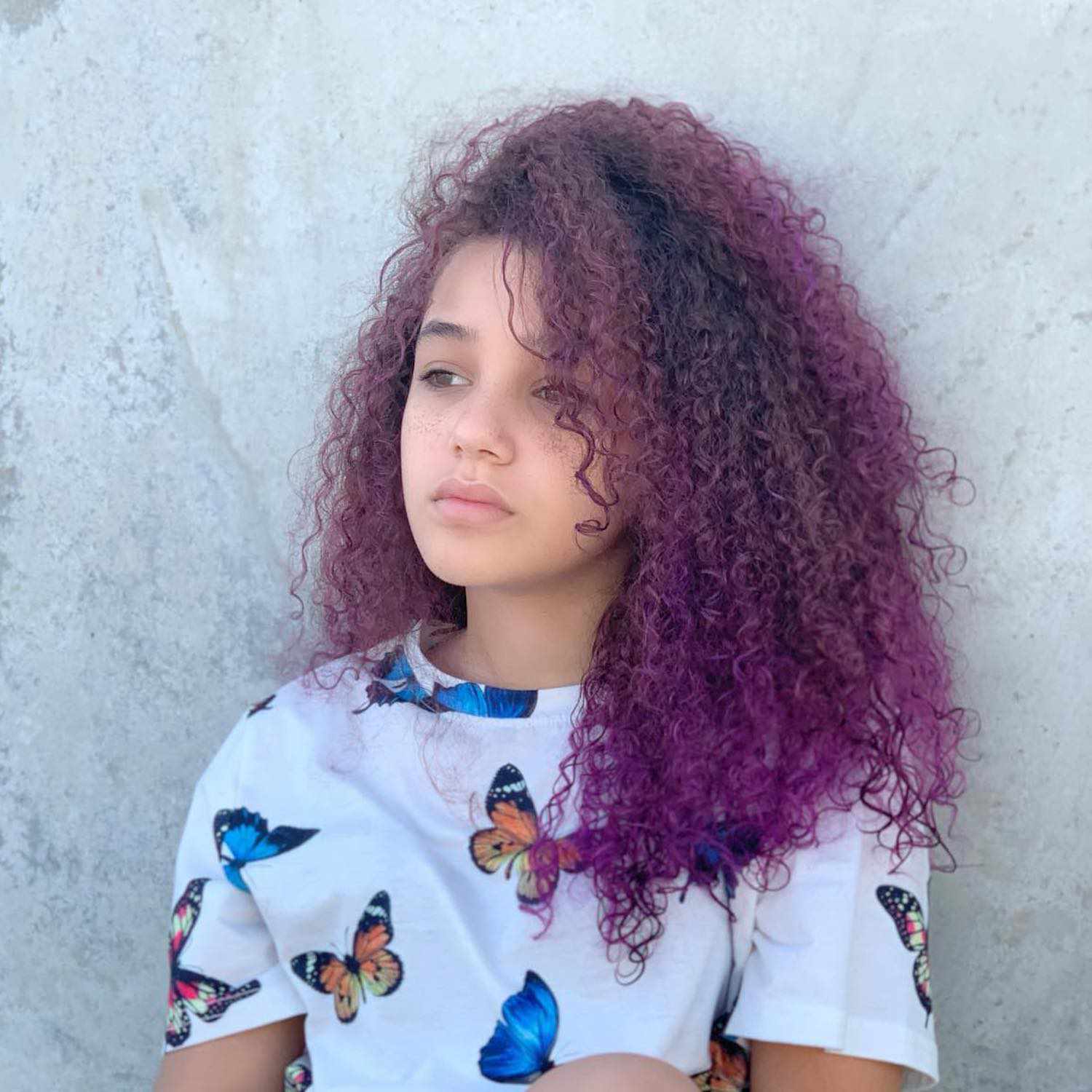 科琳快乐穿grape-colored卷发和一只蝴蝶的t恤