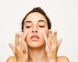 女人牙间隙应用奶油跟她脸颊的手指