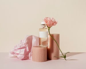 粉红色的香水瓶，上面有一188金宝搏是真的朵玫瑰花，圆柱体，还有皱褶的粉色纸