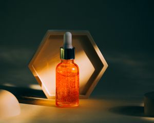 橙色玻璃滴管的血清瓶前面六角形装饰在黑暗的房间与阳光