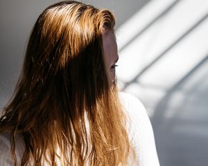 红褐色头发遮住眼睛的女人，站在阴影中