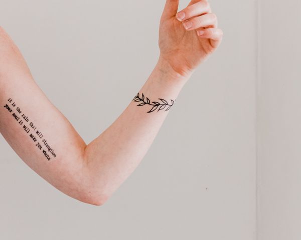 手臂上有两个纹身，一个是文字，另一个是树叶做成的手镯