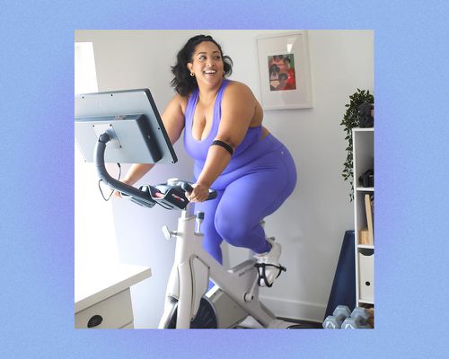 一名穿着健身服的女子在健身自行车上微笑。