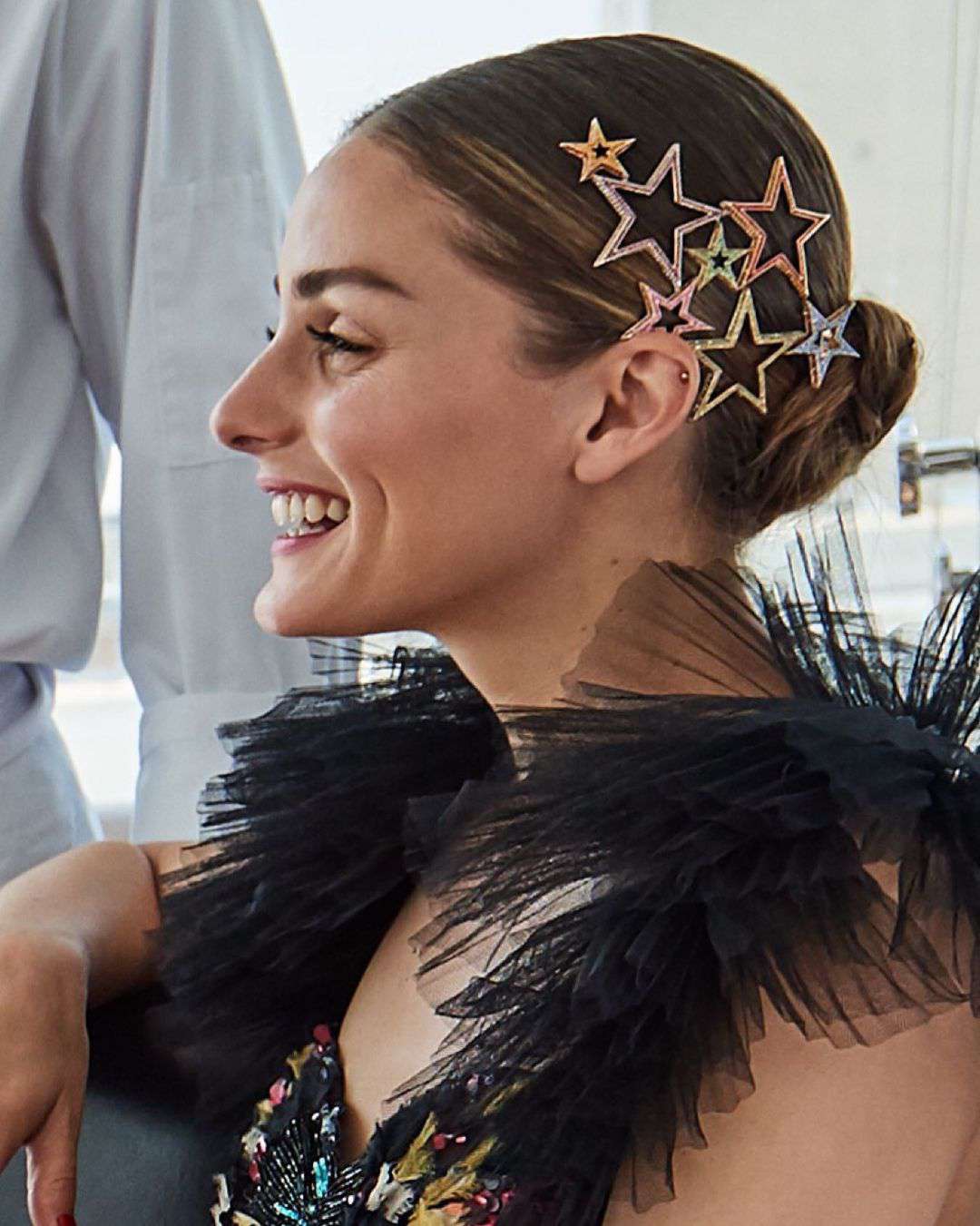 奥利维亚·巴勒莫(Olivia Palermo)戴着一个低发髻，上面有彩色的星星夹子