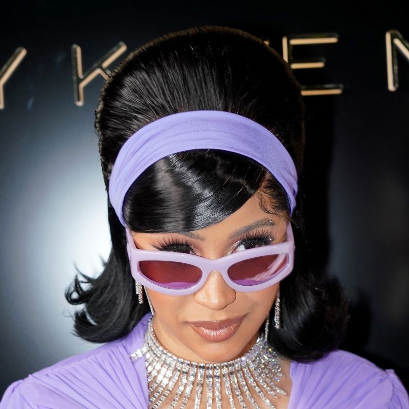 在2021年巴黎时装周上，卡迪·B梳着蓬松的发型，戴着紫色发带和配套的太阳镜，穿着紫色的衣服，戴着钻石珠宝。