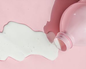 牛奶洒在粉红色的背景上