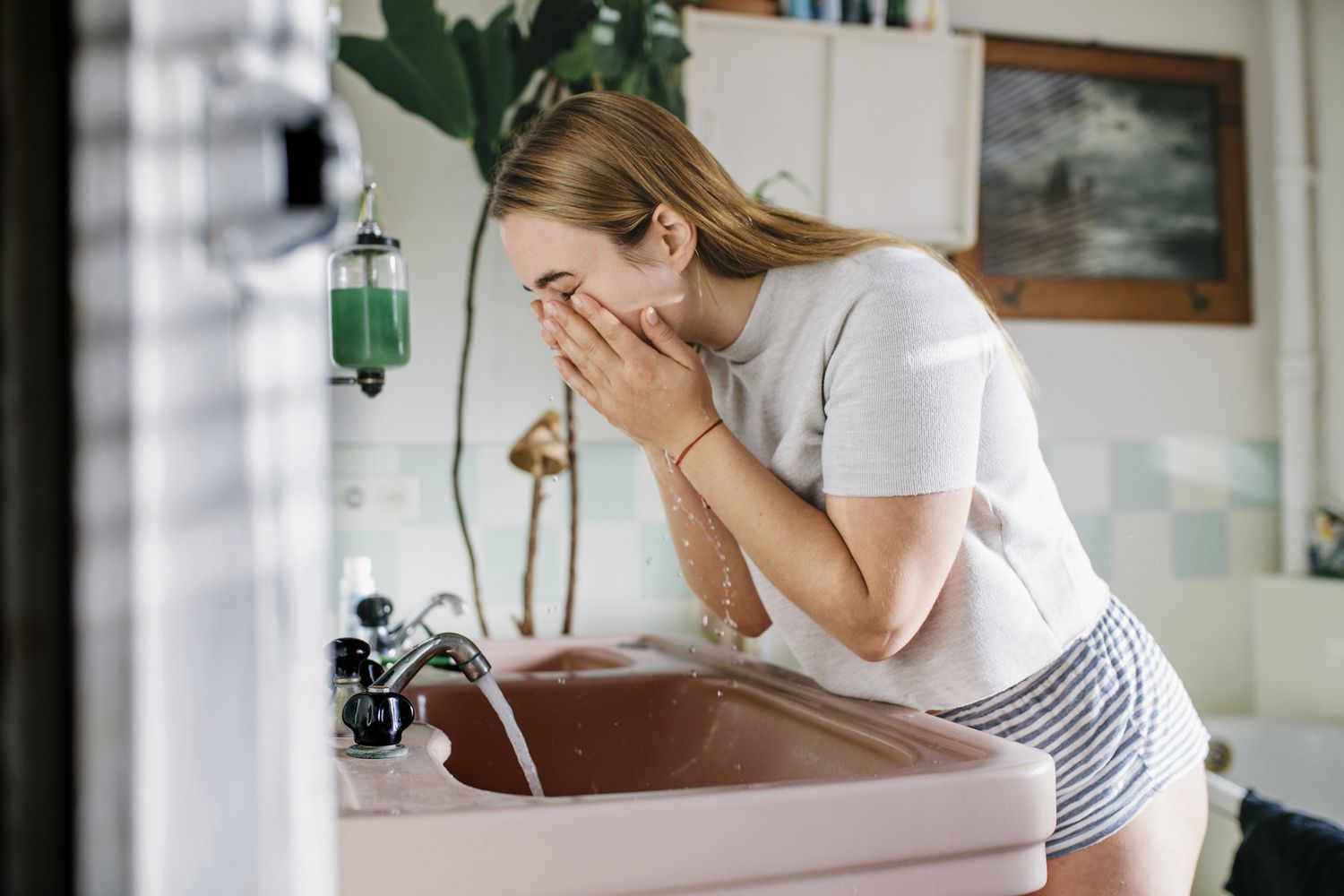 女人在粉红色的水槽洗脸