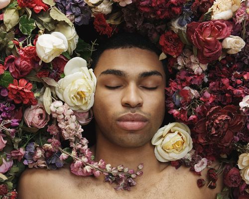 年轻人躺在鲜花,闭上眼睛,俯视