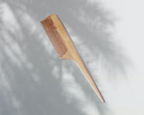 日本木制胡须梳与尾巴在灰色手掌阴影背景